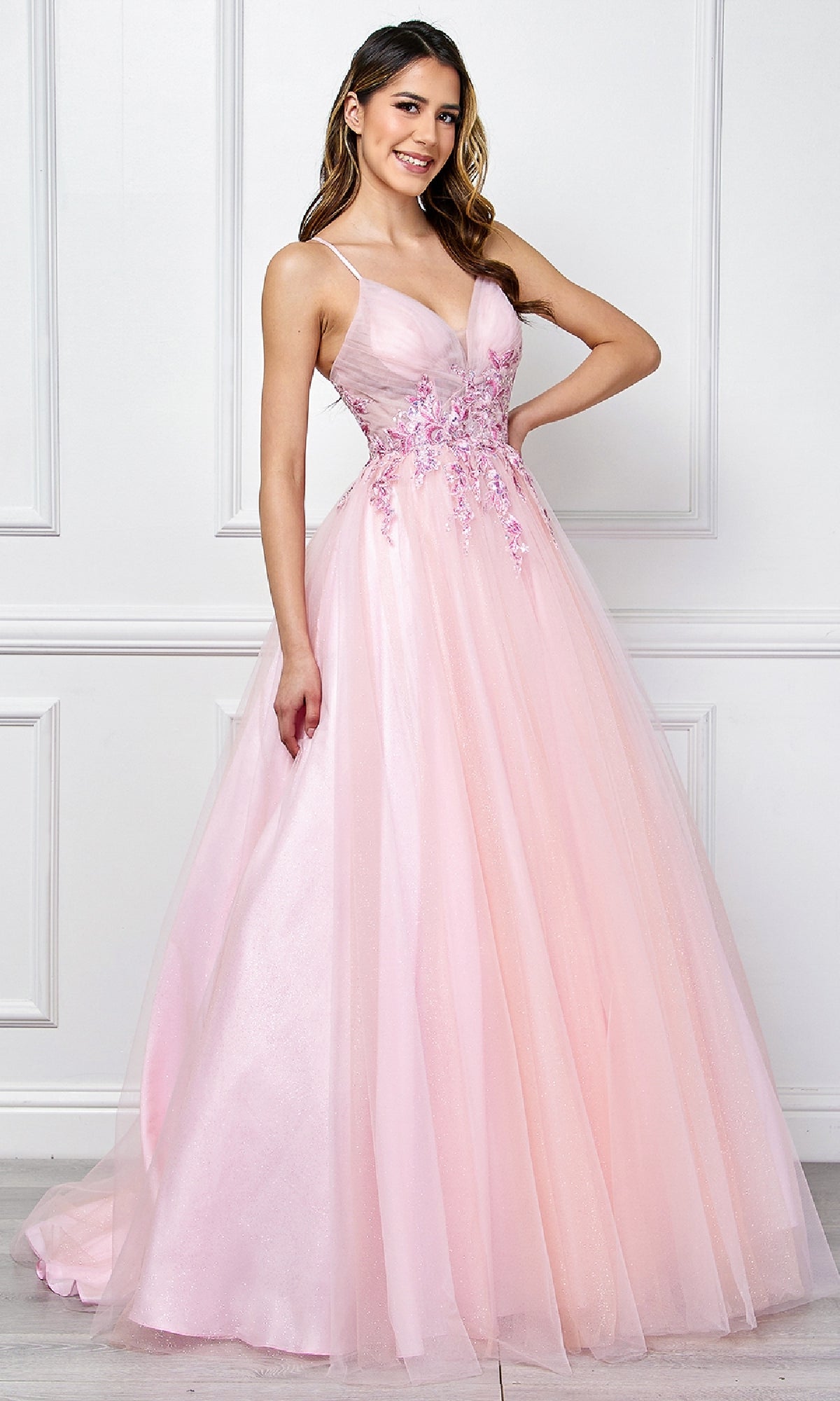 A woman stands indoors wearing the Amelia Couture SU088 Long Pastel Prom Ball Gown, a floor-length, a-line formal dress in light pink with floral embroidery and a fitted bodice.